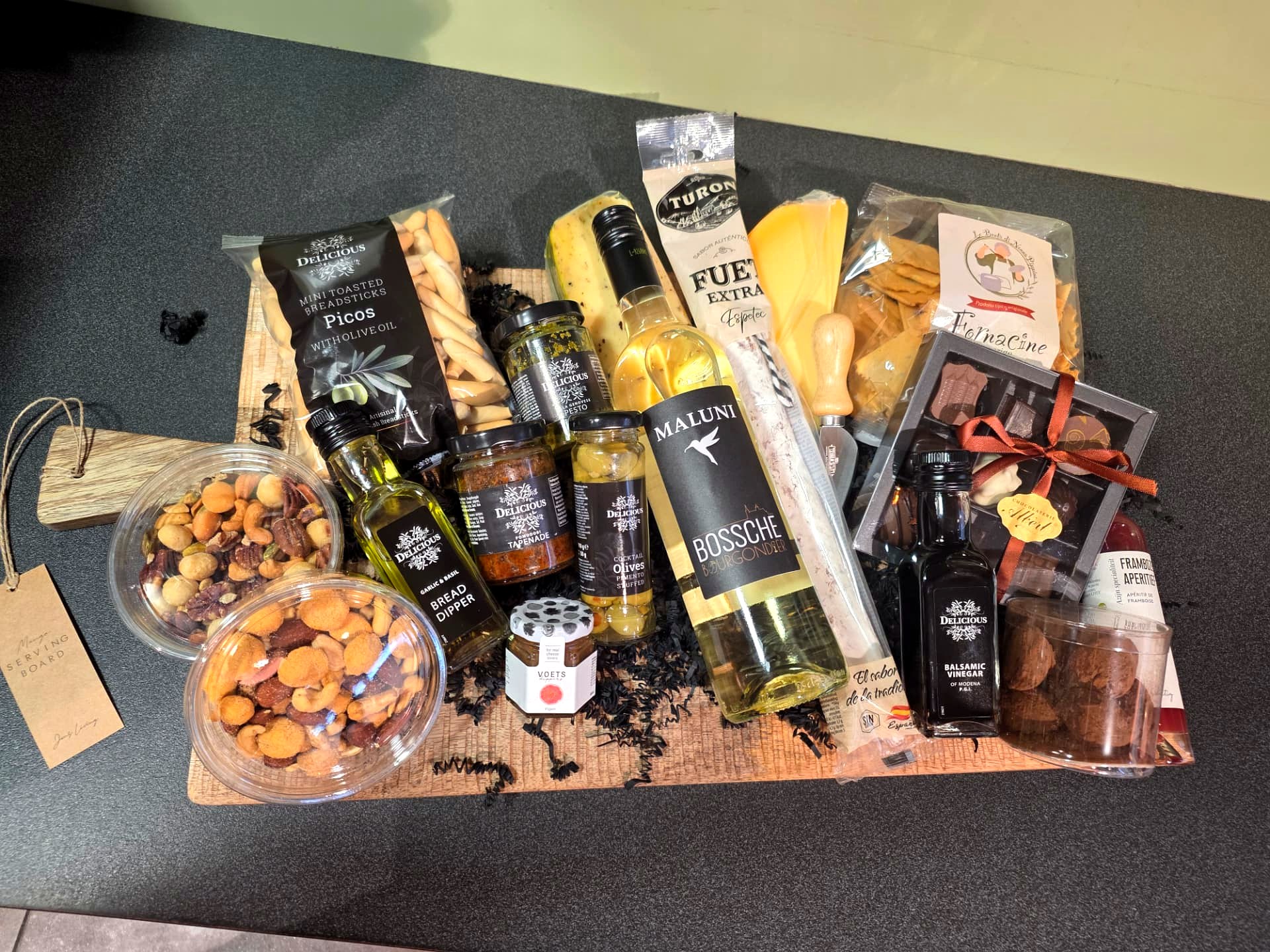 Relatiegeschenk met Bossche wijn, kaas, bonbons, noten en delicatessen op een serveerplank