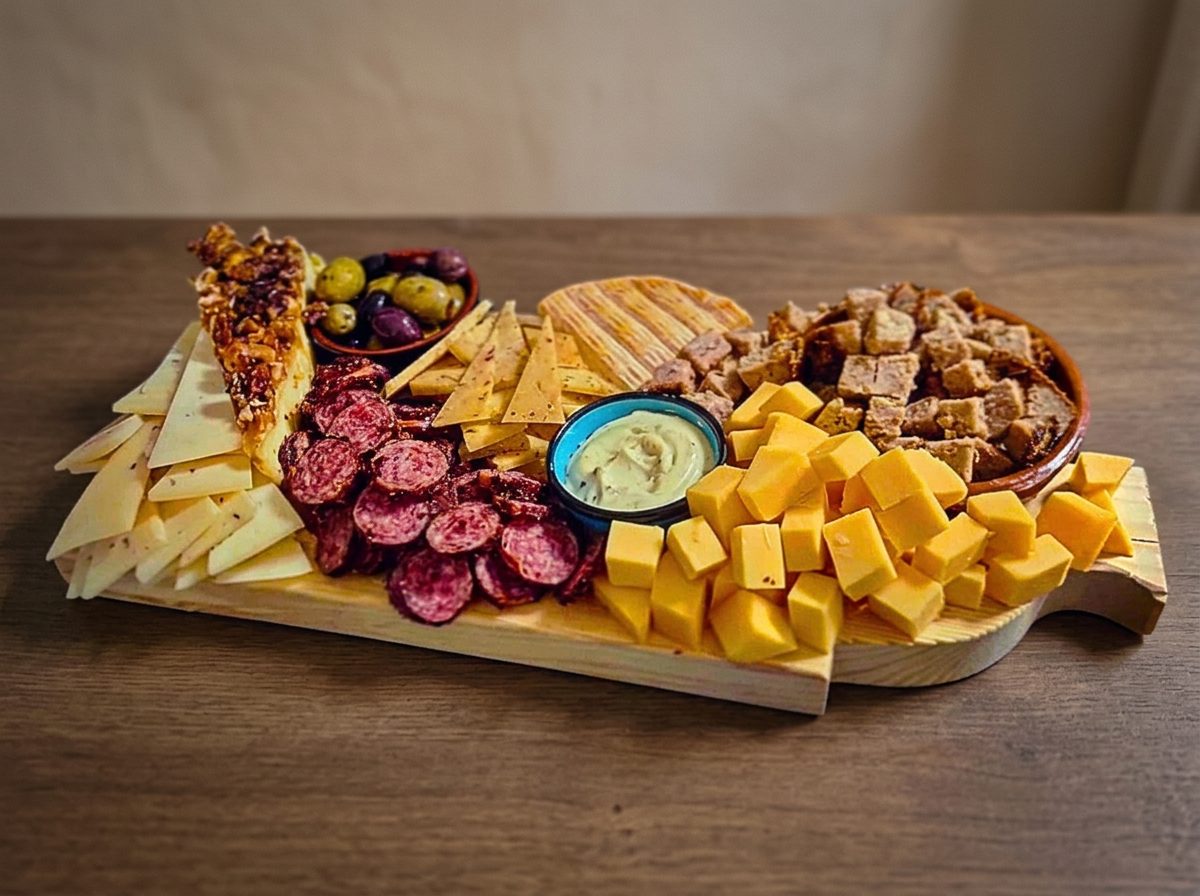Onze Deluxe borrelplank met kaas, fuet, olijven, gehaktbrood en dip op een houten tafel